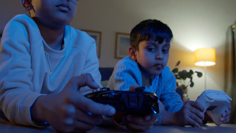 Two-Young-Boys-At-Home-Playing-With-Computer-Games-Console-On-TV-Holding-Controllers-Late-At-Night-6